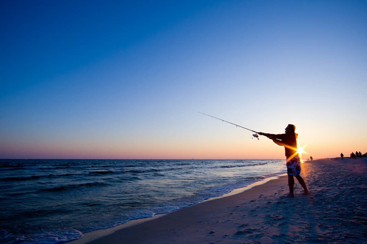 Man surf fishing at Fort Morgan Beach